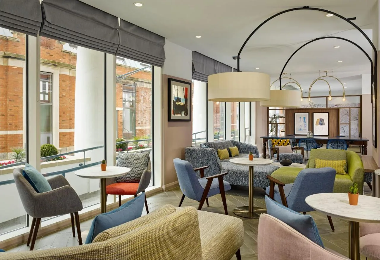 a restaurant with tables and chairs and windows at Citadines Islington London